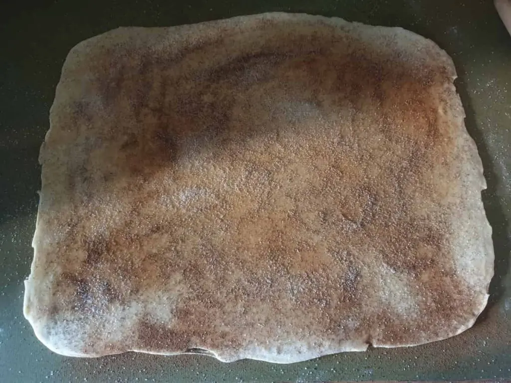 Rolling out the dough and spreading it with cinnamon