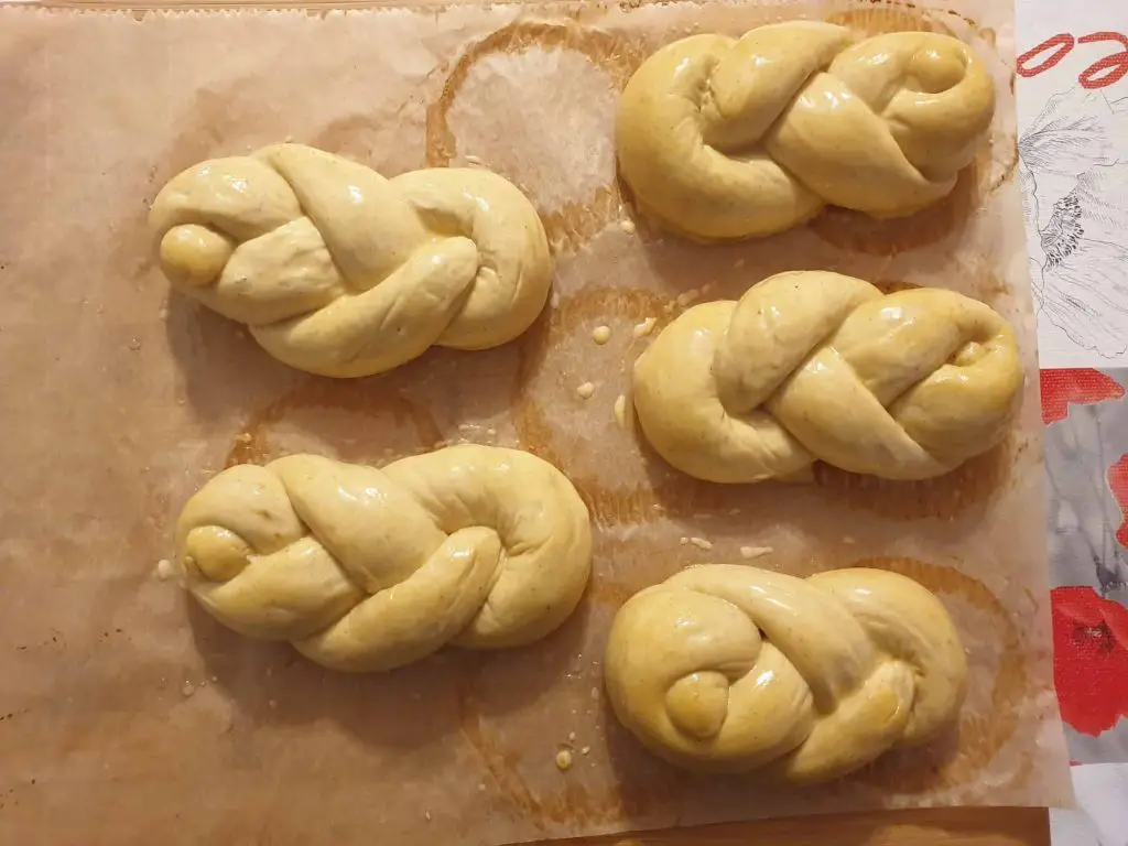 Brushing egg wash on the spiced braided bread rolls