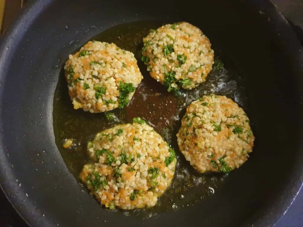 Frying the millet fritters with carotts in a pan